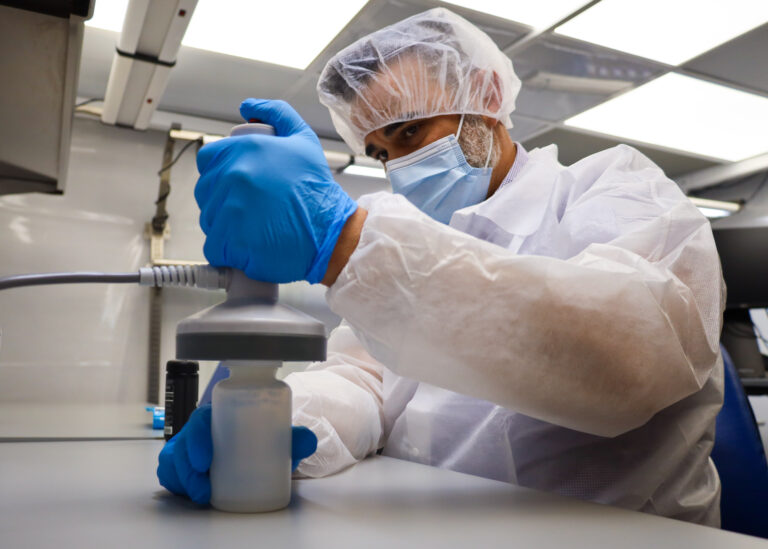 Nutraceutical Contract Packaging and Sample Fulfillment 2 Supera operator applying an induction seal to a repacked supplement bottle in a controlled packaging area